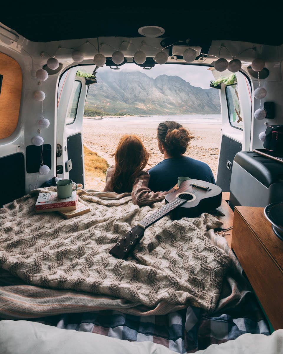 Backview of Couple sitting on a Camper Van, mobile home